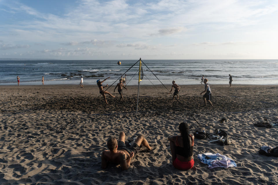 People play beach volleyball at Canggu Beach in Bali at sunset.