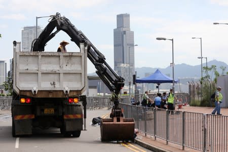 Workers clean up debris following protests over a proposed extradition bill, near the Legislative Council building in Hong Kong