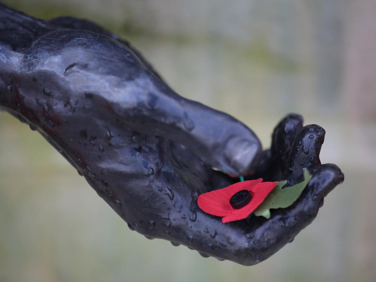 A poppy rests in the hand of a statue during the annual Armistice Day service at the National Memorial Arboretum in Staffordshire: Getty
