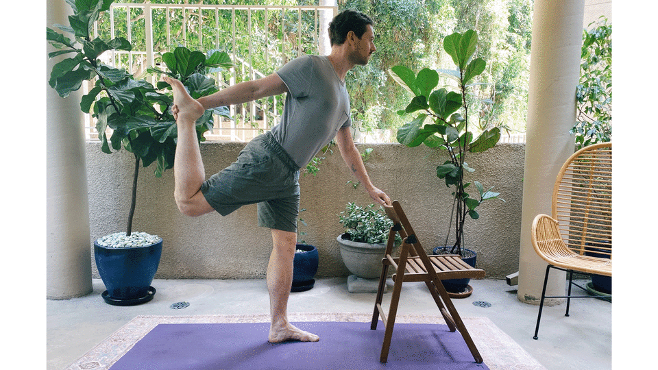 Man leaning on a chair attempting a balancing pose in yoga