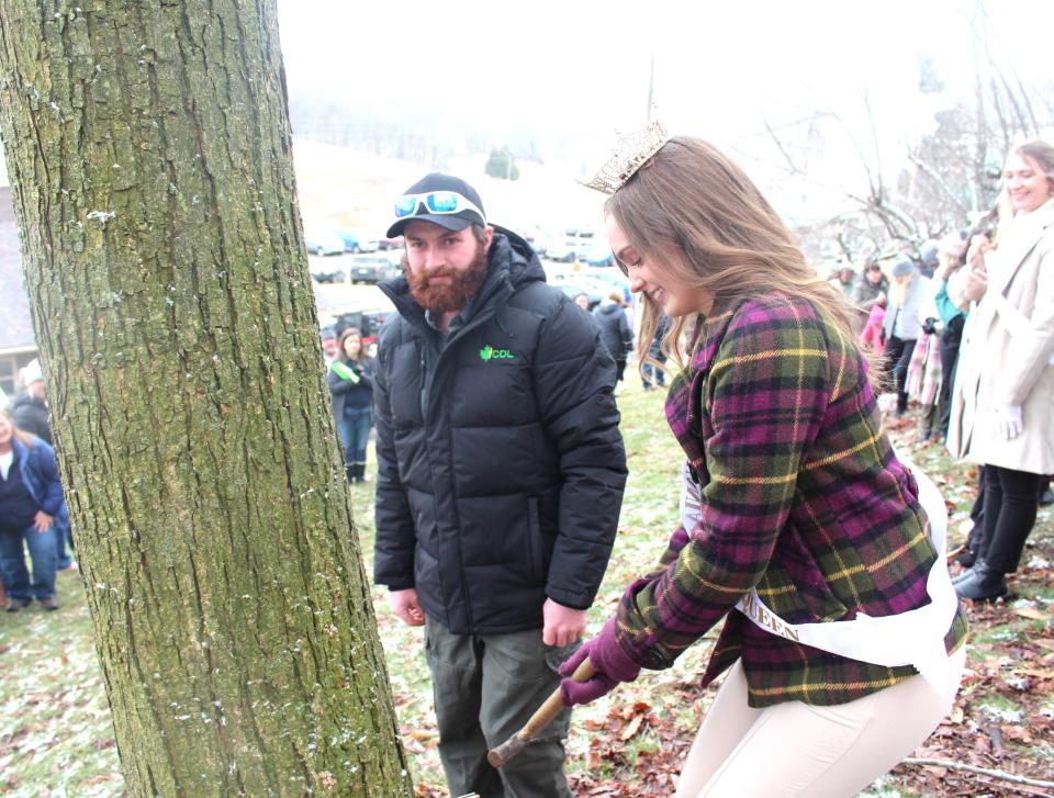 Reigning royalty 2023 Maple King Cody Lynch and Queen Maple LXXVI Laura Boyce tap the first official tree for the maple season during the tree tapping ceremony at Hillegas Maple on Dividing Ridge on Saturday. The sap did not drip from the old maple tree on the property because of colder temperatures during the day.