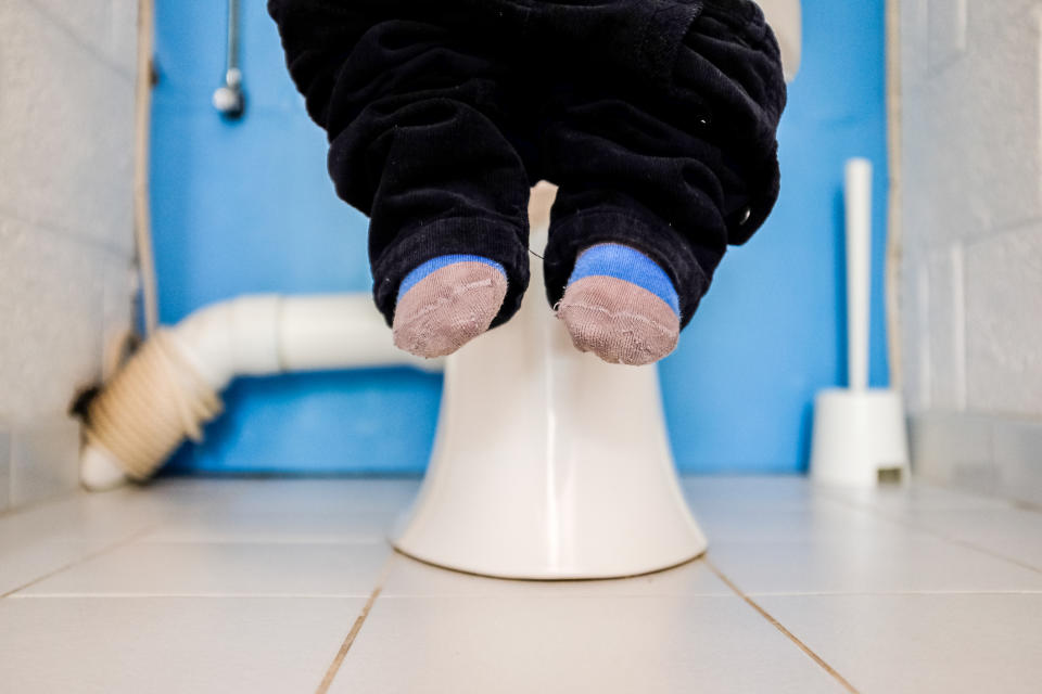 Closeup of a little boy's feet while he's sitting on the toilet