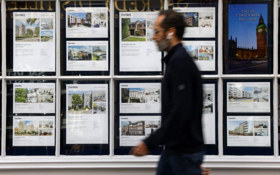 A member of the public walks past residential properties displayed for sale in the window of an estate agents' in London on September 30, 2022 - ISABEL INFANTES/AFP