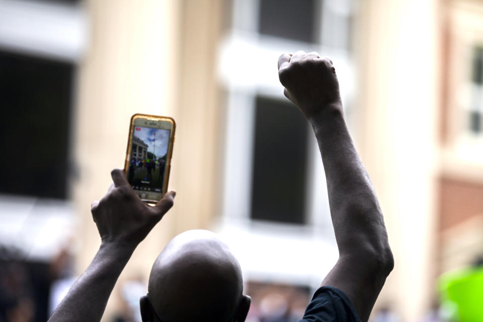 A protester raises his fist during a rally at the Glynn County Courthouse to protest the shooting of Ahmaud Arbery, Saturday, May 16, 2020, in Brunswick, Ga. (AP Photo/Stephen B. Morton)