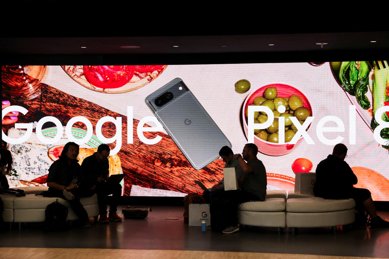 People sit in front of an ad for a new Google Pixel 8 Phone in New York City