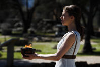 An actress, playing the role of a priestess, holds the flame during the flame lighting ceremony at the closed Ancient Olympia site, birthplace of the ancient Olympics in southern Greece, Thursday, March 12, 2020. Greek Olympic officials are holding a pared-down flame-lighting ceremony for the Tokyo Games due to concerns over the spread of the coronavirus. Both Wednesday's dress rehearsal and Thursday's lighting ceremony are closed to the public, while organizers have slashed the number of officials from the International Olympic Committee and the Tokyo Organizing Committee, as well as journalists at the flame-lighting. (AP Photo/Thanassis Stavrakis)