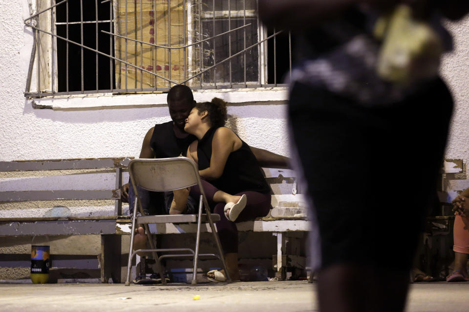 In this July 28, 2019, photo, a woman from Nicaragua embraces a man from Africa under the patio floodlights at El Buen Pastor shelter for migrants in Cuidad Juarez, Mexico. (AP Photo/Gregory Bull)