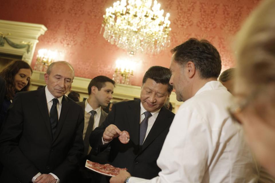 Chinese President Xi Jinping, center, tastes local food during a visit before a dinner at the town hall in Lyon, central France, Tuesday, March 25, 2014. Xi Jinping arrived in France for a three-day state visit. (AP Photo/Laurent Cipriani, Pool)