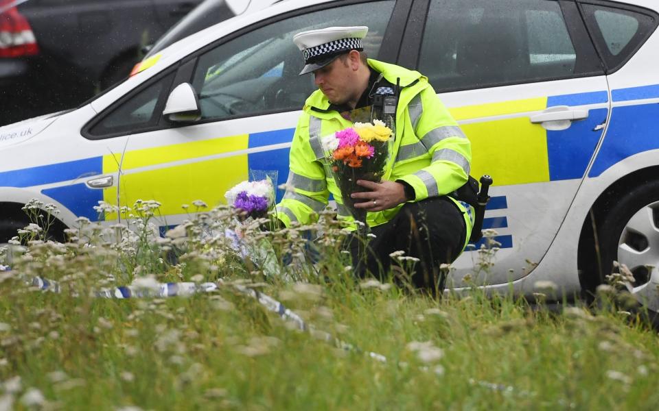 A police officer lays flowers at the scene (EPA)