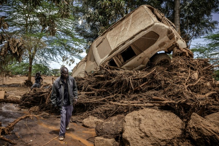 Un homme passe près d'une voiture emportée par l'inondation dans le village de Kamuchiri (Kenya), près de Mai Mahiu, le 29 avril 2024 (LUIS TATO)