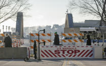 Pedestrians made their way across a closed street near the heavily gated Warren E. Burger Federal Building as jury selection begins in the trial of ex-Minneapolis officers charged in George Floyd killing in St. Paul, Minn., Thursday, Jan. 20, 2021. Jury selection began Thursday in the federal trial of three Minneapolis police officers charged in George Floyd’s killing, with the judge stressing repeatedly that fellow Officer Derek Chauvin's conviction on state murder charges and guilty plea to a federal civil rights violation should not influence the proceedings. (Elizabeth Flores/Star Tribune via AP)