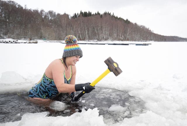 Alice Goodridge, from Newtonmore, uses a sledgehammer to create a channel in the ice to swim in Loch Inch, in the Cairngorms National Park