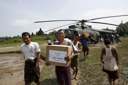 Storm victims carry aid from a military helicopter at Mrauk-U township, Rakhine state, August 5, 2015. REUTERS/Soe Zeya Tun