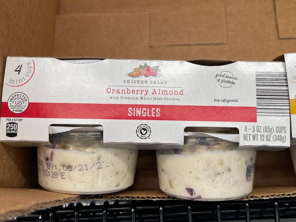 Two containers of chicken salad with gray cardboard packaging holding the two together