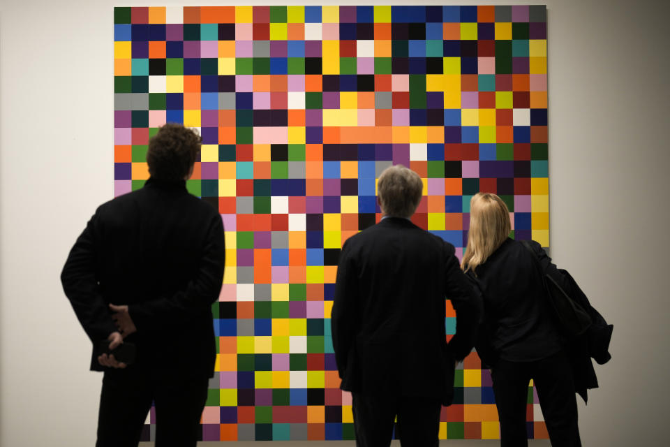 People looks at painting '4900 Colours (excer pt)' in a new exhibition with art works of German artist Gerhard Richter at the New National Gallery in Berlin, Germany, Friday, March 31, 2023. Richter's foundation gave on permanent loan 100 works of the artist to the New National Gallery where they will be shown in the permanent exhibition. (AP Photo/Markus Schreiber)