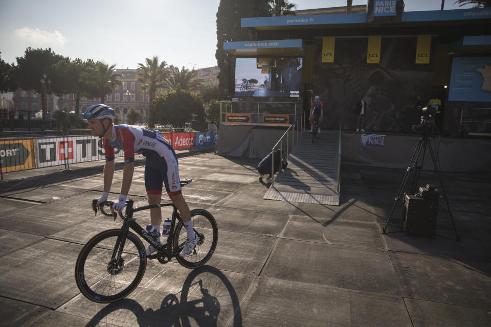 Total Direct Energie's D Van Gestel, of Belgium, rides through an empty presentation venue in Nice, southern France, before the start of the seventh stage of the Paris Nice cycling race. The eighth and final stage of the event was cancelled and spectators are prevented from attending the race due to measures in place to prevent the spread of the Covid-19 virus. For most people, the new coronavirus causes only mild or moderate symptoms. For some it can cause more severe illness. Stage seven runs just over 166 kilometers starting in Nice and finishing in Valdeblore La Colmiane, France, Saturday, March 14, 2020. (AP Photo/Daniel Cole)