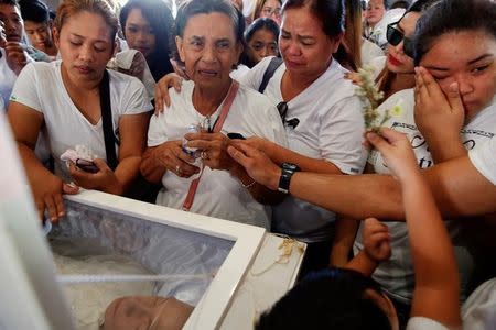 The mother, wife, and other relatives of Florjohn Cruz, who was killed in a police drugs buy-bust operation, mourn by his coffin during his funeral in Manila, Philippines October 30, 2016. REUTERS/Damir Sagolj/Files