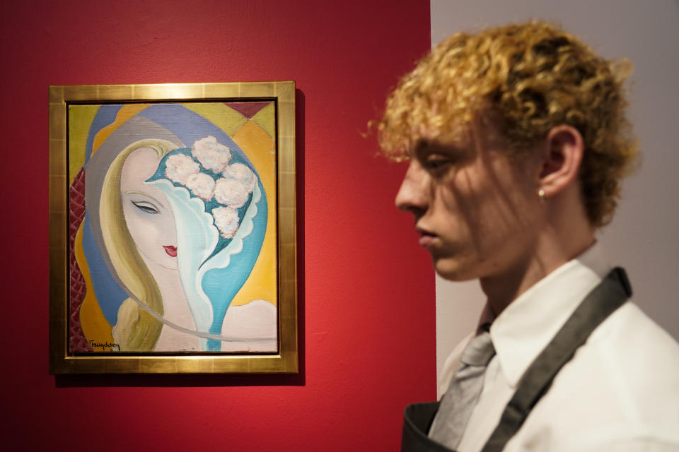 A member of staff stands next to the original artwork by E. Frandsen De Schomberg, used for the cover of Derek and the Dominoes album 'Layla and Other Assorted Love Songs' as part of The Pattie Boyd Collection at Christie's, in London, Thursday, March 14, 2024. The artwork is estimated to sell £40,000-60,000. (AP Photo/Alberto Pezzali)