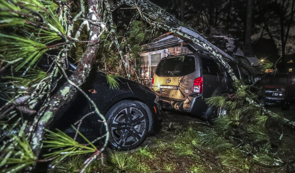 Fallen tree branches cover a yard and vehicles on Friday, Feb. 4, 2022 in Atlanta. A major winter storm that already cut electric power to about 350,000 homes and businesses from Texas to the Ohio Valley is now causing misery in the Northeast. (John Spink /Atlanta Journal-Constitution via AP)