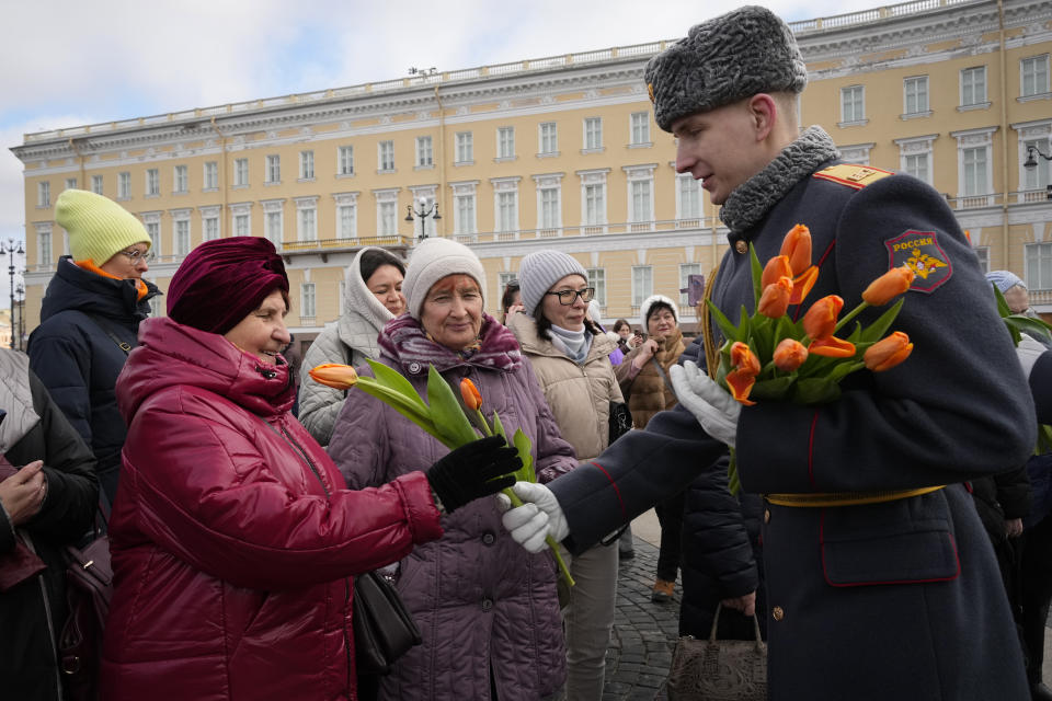 A honour guard soldier gives flowers to women on International Women's Day in St. Petersburg, Russia, Friday, March 8, 2024. International Women's Day on March 8 is an official holiday in Russia. Per tradition, men give flowers and gifts to female relatives, friends and colleagues, even though in the past two years flowers have gotten more expensive. Marches, demonstrations and conferences are being held the world over, from Asia to Latin America and elsewhere. (AP Photo/Dmitri Lovetsky)