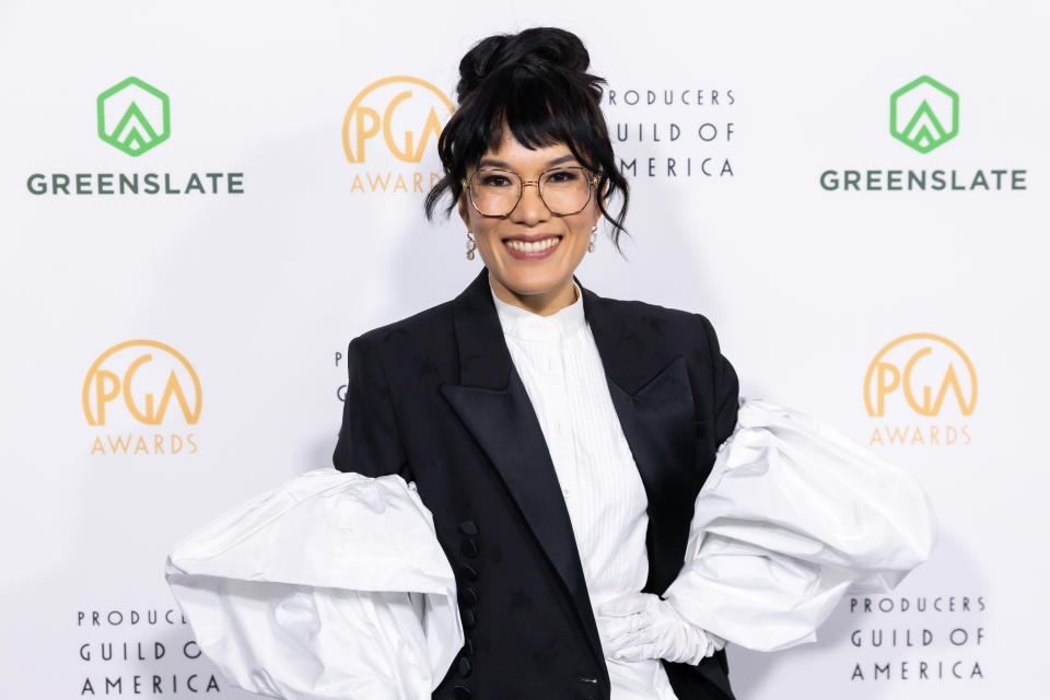Ali Wong smiling, wearing a black suit with large white ruffled sleeves at the Producers Guild Awards