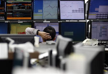 An employee of a foreign exchange trading company looks at monitors in Tokyo March 18, 2014. REUTERS/Toru Hanai