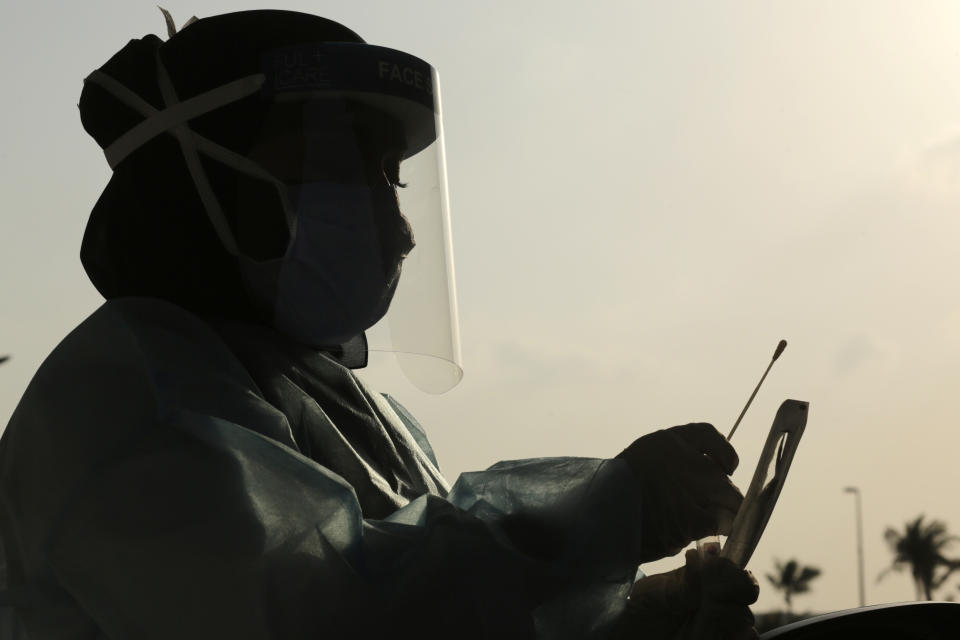 Saudi health worker, Wedad Modaifen collects a swab sample for a polymerase chain reaction (PCR) test at drive-through testing center, at King Abdulaziz University in Jiddah, Saudi Arabia Wednesday, Feb. 3, 2021. In Saudi Arabia, where authorities already have banned travel to the kingdom from 20 countries including the U.S., officials ordered all weddings and parties suspended. It closed down all shopping malls, gyms and other locations for 10 days, as well as indoor dining. (AP Photo/Amr Nabil)