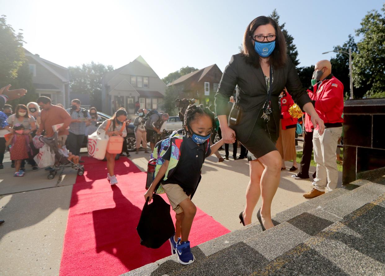 MacDowell Montessori School principal Andrea Corona walks a student into school during the first day of school at MacDowell Montessori School.