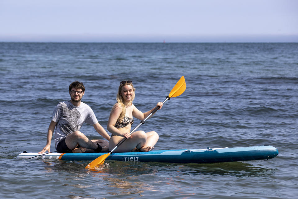 <p>Aneurin Duffin-Murray (left) and Lauren Dalzell from Belfast on a paddle board at Helen�s Bay beach in County Down, Northern Ireland. Picture date: Tuesday July 20 2021.</p>
