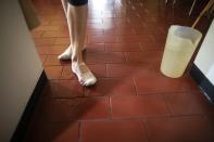 Carolina Wolf, who dances with Venezuela's national ballet, wets her ballet shoes with a little water so as not to slip during her training session in her living room during a lockdown to curb the spread of COVID-19 in Caracas, Venezuela, Tuesday, Aug. 11, 2020. The 42-year-old ballerina said her living room is four times smaller than the studio where she practiced daily at the famed Teresa Carreño Theater, and she doesn't dare do jumps in fear of injuring herself on the hard floor. (AP Photo/Ariana Cubillos)