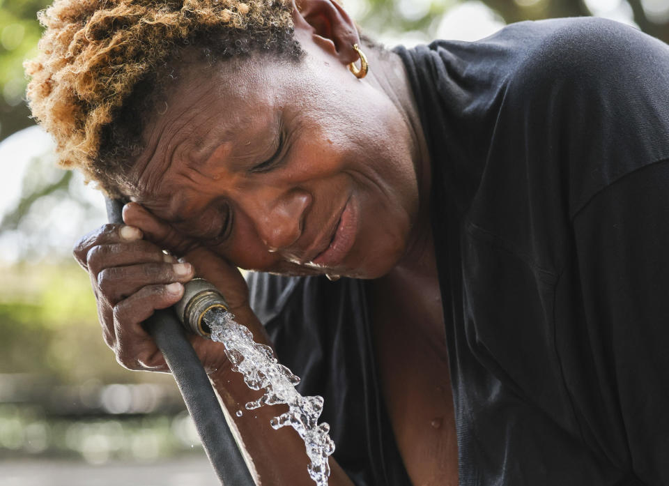 Judy Breland Morris cools off and washes herself off with a hose after she claims she was maced near Jackson Square, during an excessive heat warning in New Orleans, Tuesday, June 27, 2023. (Sophia Germer/The Times-Picayune/The New Orleans Advocate via AP)