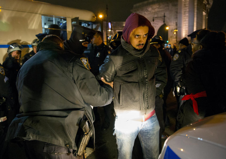 A person is taken into custody at the Manhattan side of the Manhattan Bridge Thursday, Dec. 4, 2014, in New York, after several protesters were arrested as they tried to block the bridge entrance protesting against a grand jury's decision not to indict the police officer involved in the death of Eric Garner. A grand jury cleared a white New York City police officer Wednesday in the videotaped chokehold death of Garner, an unarmed black man, who had been stopped on suspicion of selling loose, untaxed cigarettes, a lawyer for the victim's family said. (AP Photo/Craig Ruttle)