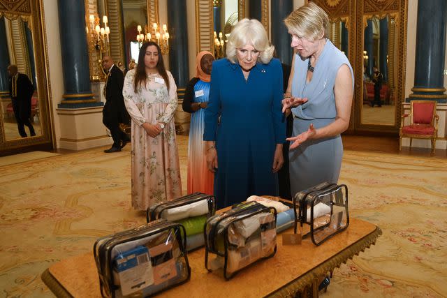 <p>Eamonn M. McCormack - Pool/Getty</p> Queen Camilla (center) views toiletry bags at the Buckingham Palace reception on May 1, 2024.