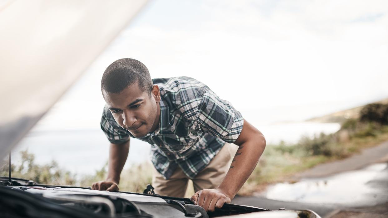 Cropped shot of a young man with his broken down car on the side of a road.