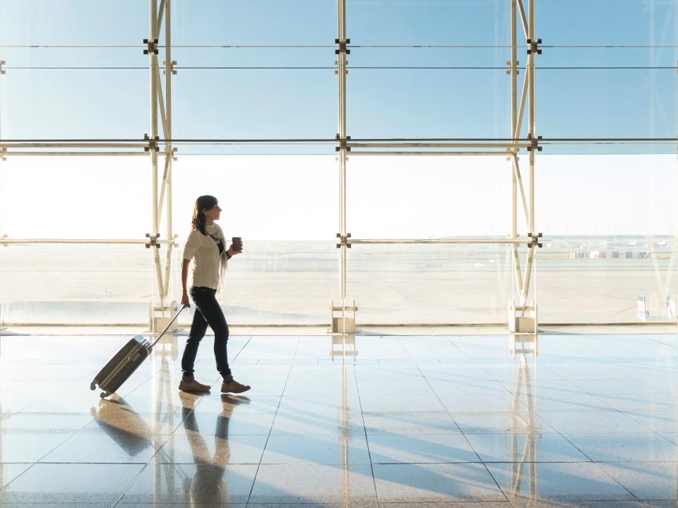 Woman walking through an airport with her suitcase.