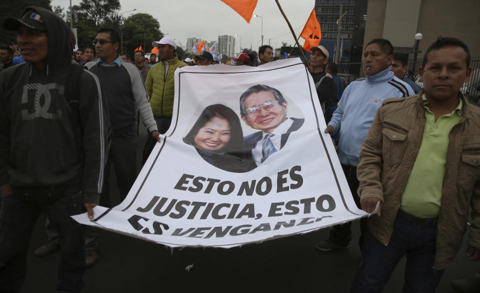 Supporters of Peru's former President Alberto Fujimori and his daughter Keiko march with a poster of them that reads in Spanish: "This is not justice, it's revenge" in Lima, Peru, Monday, Oct. 15, 2018. Keiko was detained last week as part of a money-laundering investigation and a judge ordered her father returned to jail to finish a 25-year sentence for human rights abuses. (AP Photo/Martin Mejia)