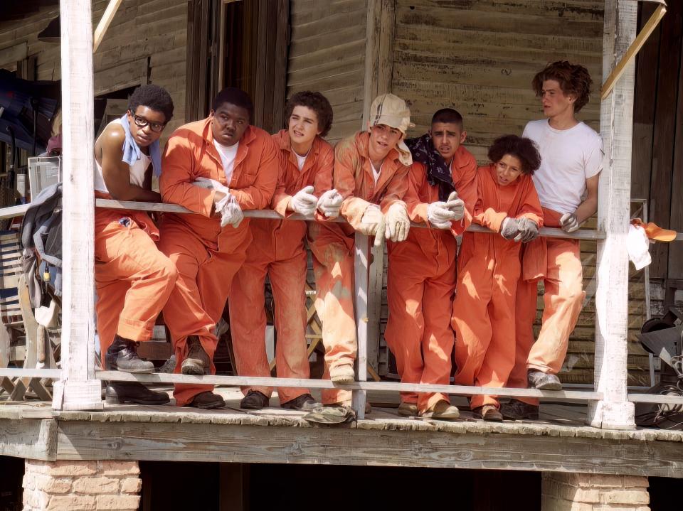 the kids filming a scene in holes in their orange jumpsuits