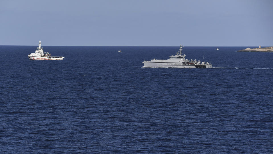 An Italian Finance Police vessel patrols around the Open Arms vessel, left, with 107 migrants on board, as it is anchored off the Sicilian vacation and fishing island of Lampedusa, southern Italy, Monday, Aug. 19, 2019. Open Arms on Monday suggested chartering a plane to fly to Spain the migrants blocked off the coast of Italy aboard its boat since early August, to end a stalemate with the Italian Interior minister Matteo Salvini, who won't let private rescue boats into his nation's ports. (AP Photo/Salvatore Cavalli)