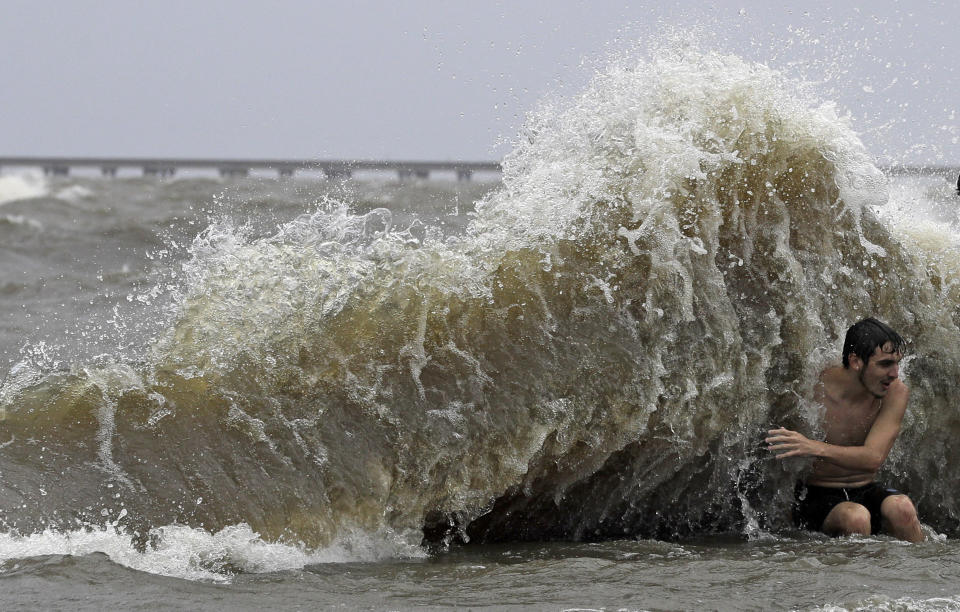 Brady Dayries is hit by a wave as winds from Tropical Storm Barry push water from Lake Pontchartrain over the seawall Saturday, July 13, 2019, in Mandeville, La. (AP Photo/David J. Phillip)