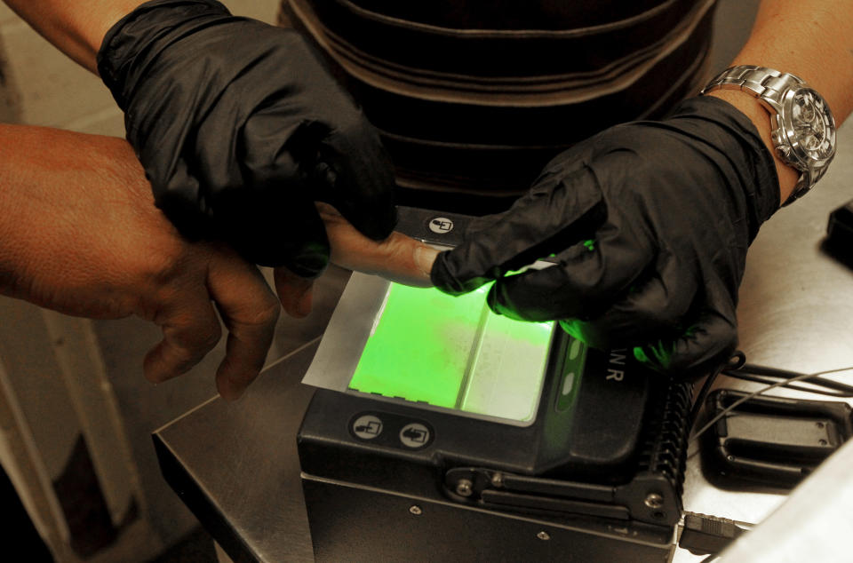 An illegal immigrant is fingerprinted as part of processing in order to create or update a file on that immigrant at Tucson Sector U.S. Border Patrol Headquarters Thursday, Aug. 9, 2012, in Tucson, Ariz. The U.S. government has halted flights home for Mexicans caught entering the country illegally in the deadly summer heat of Arizona's deserts, a money-saving move that ends a seven-year experiment that cost taxpayers nearly $100 million.(AP Photo/Ross D. Franklin)