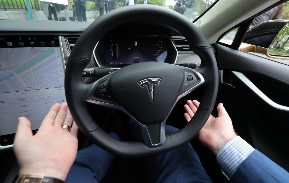 A driver takes his hands off the wheel of his Tesla Model S car at a launch event for the MobilityX self-driving conference.