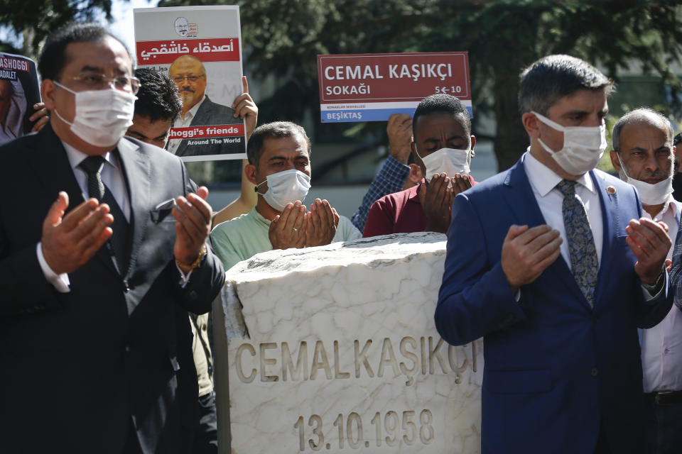 Colleagues of slain Saudi journalist Jamal Khashoggi, offer their prayers next to a monument, near the Saudi Arabia consulate in Istanbul, marking the two-year anniversary of his death, Friday, Oct. 2, 2020. The gathering was held outside the consulate building, starting at 1:14 p.m. (1014 GMT) marking the time Khashoggi walked into the building where he met his demise. (AP Photo/Emrah Gurel)