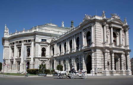 A traditional Fiaker horse carriage passes Burgtheater theatre in Vienna