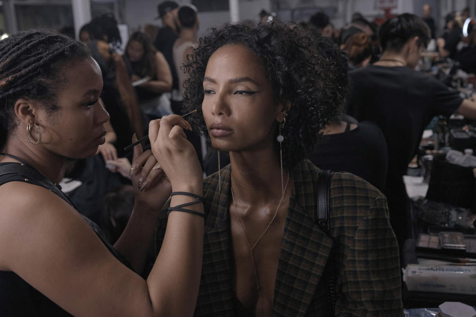A a makeup artist works on a model backstage at the LaQuan Smith show during Fashion Week on Monday, Sept. 12, 2022 in New York. (AP Photo/Andres Kudacki)