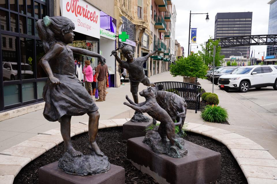 A statue of children playing with a cat and dog can been seen along S. Kansas Avenue.