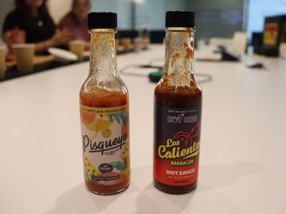 Two bottles of hot sauce on a table.