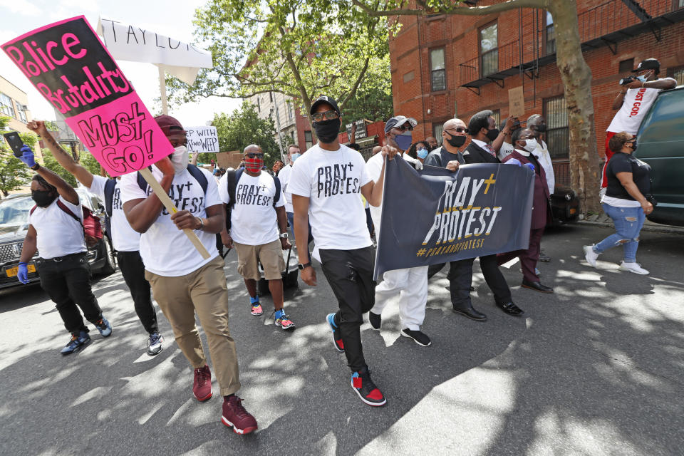 Rev. Brandon Watts, center, pastor of Brooklyn's Epiphany Church, holds a sign as he and other religious leaders lead a "Protest and Pray" rally and march, Sunday, June 7, 2020, in the Beford Stuyvesant neighborhood of New York. The march comes in the wak of the May 25 death of George Floyd at the hands of four Minneapolis police officers, one of who pressed his knee into Floyd's neck for more than eight minutes. (AP Photo/Kathy Willens)