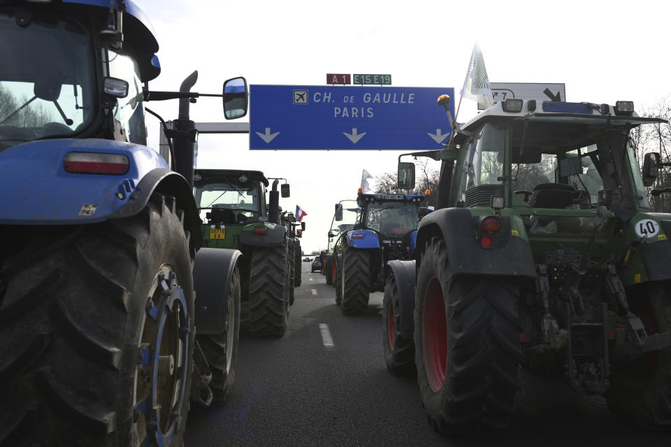 Farmers drive their tractors a highway leading to Paris's main airport, Monday, Jan. 29, 2024 near Chamant, north of Paris. Protesting farmers vowed to encircle Paris with tractor barricades and drive-slows on Monday, aiming to lay siege to France's seat of power in a battle with the government over the future of their industry, which has been shaken by repercussions of the Ukraine war. (AP Photo/Matthieu Mirville)