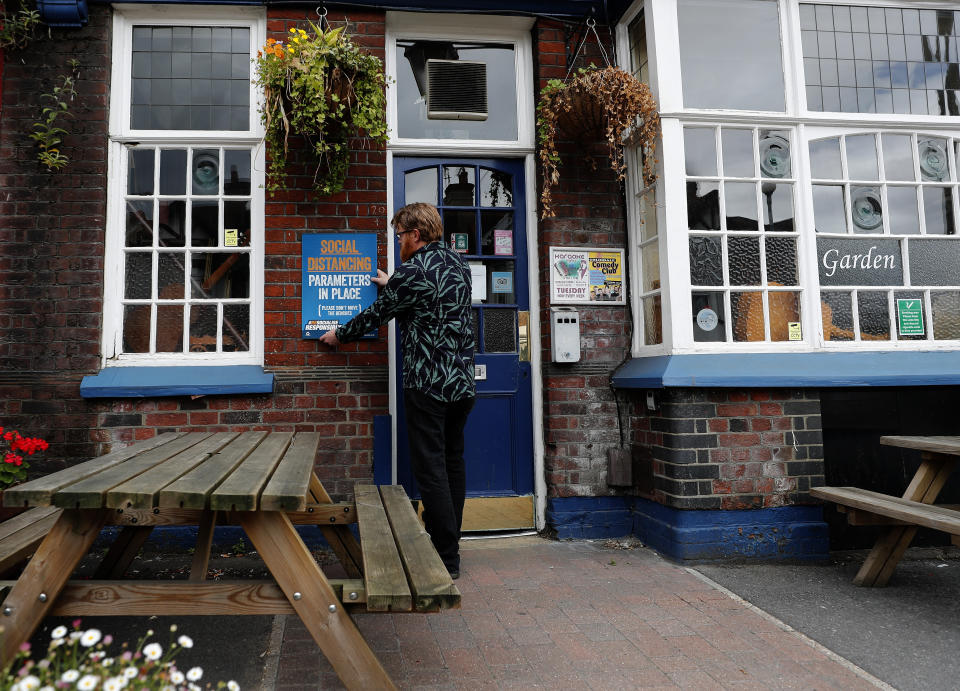 Owner Are Kjetil Kolltveit from Norway put signs in place instructing on social distancing at the Chandos Arms pub in London, Wednesday, July 1, 2020. Asking people in English pubs to keep their distance is going to be tough after they’ve had a few of their favorite tipples. Pub managers will have to be resourceful come Saturday, July 4, 2020, when they and other parts of the hospitality industry in England open their doors to customers for the first time since March 20, provided they meet COVID safety requirements. (AP Photo/Frank Augstein)