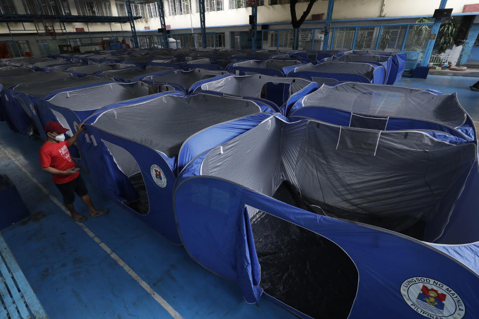 A man walks past tents set-up at a school converted into an evacuation center as they prepare for Typhoon Vamco in Manila, Philippines on Wednesday, Nov. 11, 2020. Typhoon Vamco blew closer Wednesday to a northeastern Philippine region still struggling to recover from a powerful storm that left a trail of death and destruction just over a week ago, officials said, adding that thousands of villagers were being evacuated again to safety. (AP Photo/Aaron Favila)